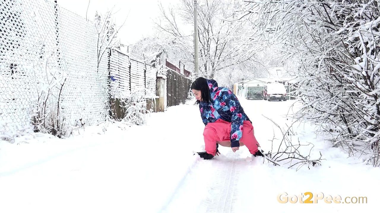 Caucasian girl Henna pulls down pink pants to pee on a snow-covered street  